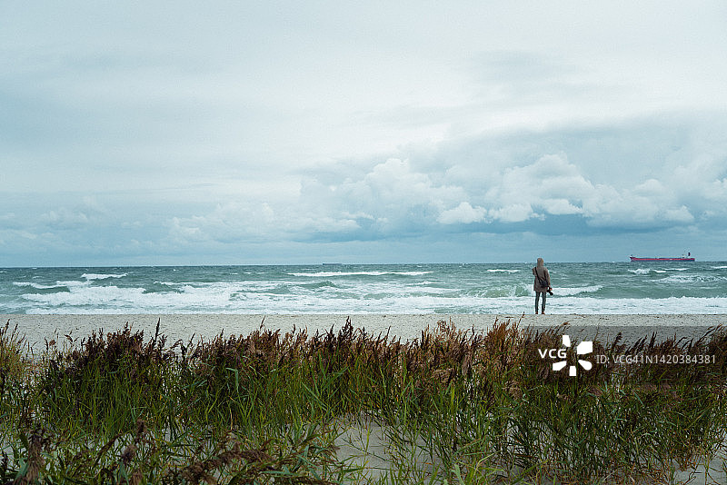在沙滩上走过远处沙丘的年轻男人图片素材