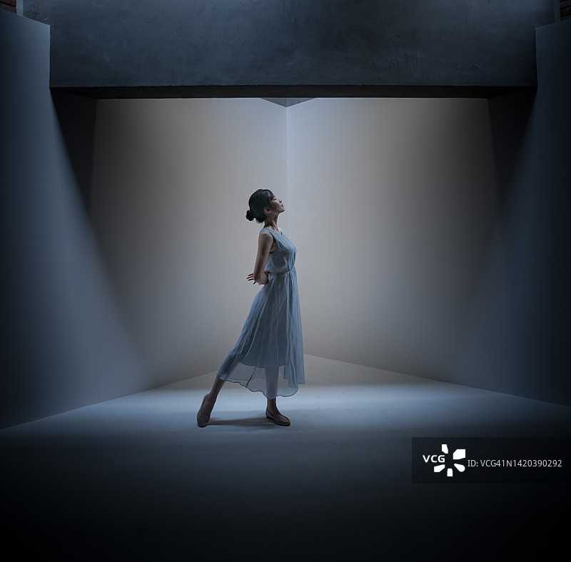 年轻女子身穿蓝色连衣裙在舞台上跳舞图片素材