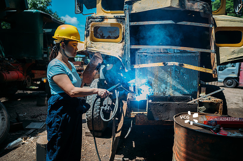 亚洲女工在车间用焊接枪切割金属板图片素材