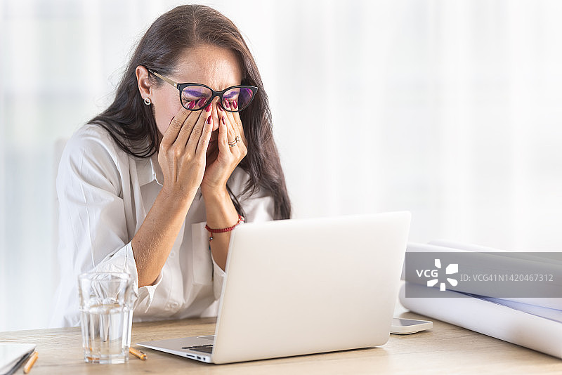 在办公室因长时间电脑工作而揉眼睛的女人图片素材