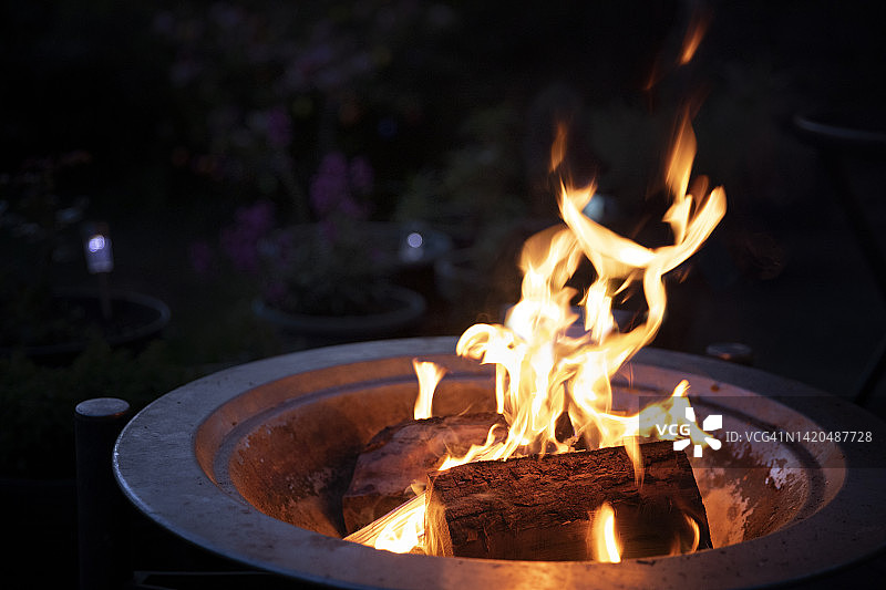 夜晚后院金属火盆中燃烧的木柴图片素材