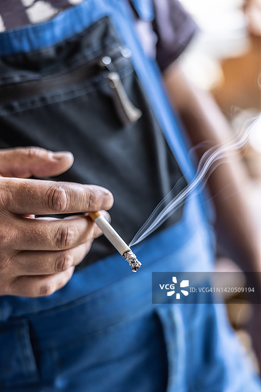 工人穿着工作服抽烟的细节图片素材