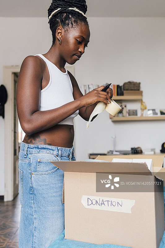 女人用胶带在床上打包捐赠箱图片素材