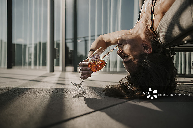 迷人的女子在阳台上倒立，用吸管喝饮料图片素材