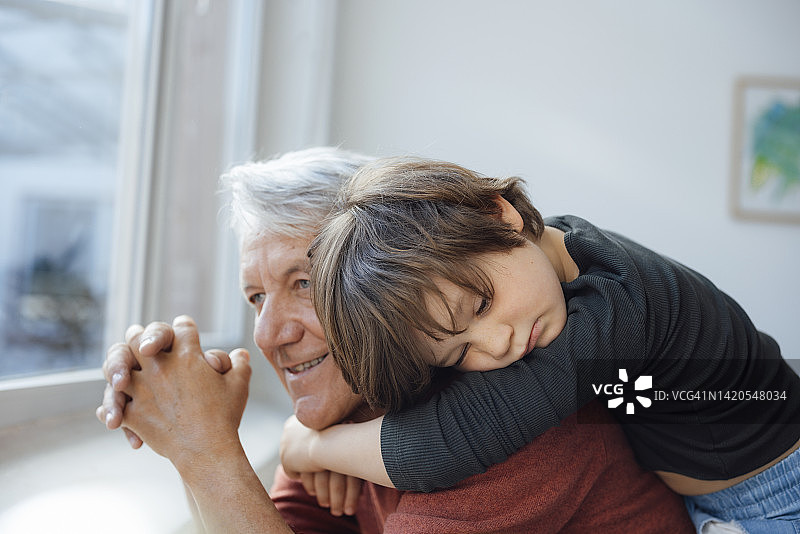 沉思的男孩在家拥抱祖父图片素材