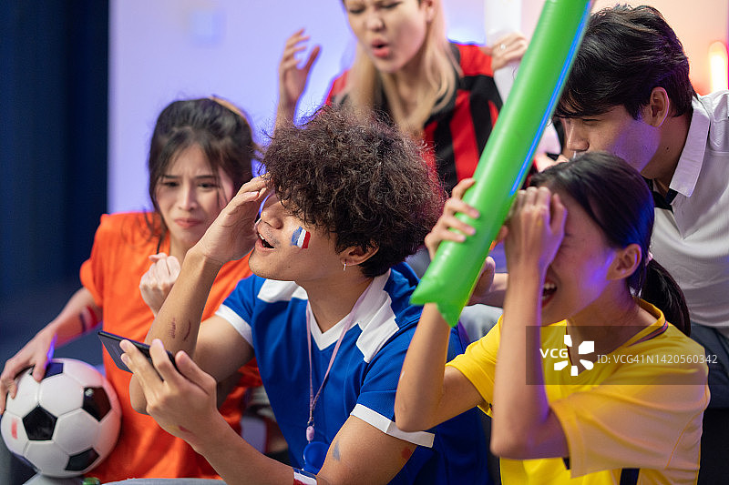 一群亚洲朋友正在用智能手机观看和欢呼足球比赛，为失利的球队加油图片素材