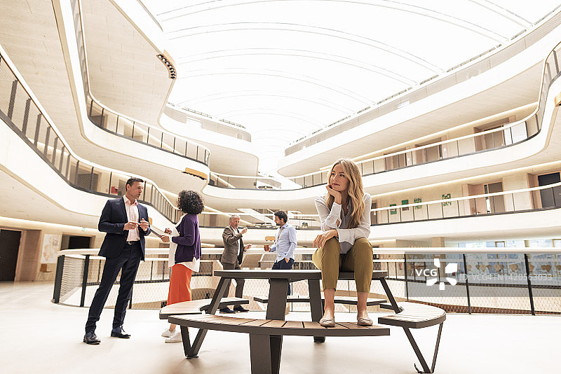沉思的女商人与同事坐在桌旁图片素材