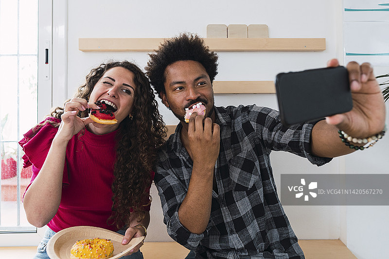 商人与在自助餐厅吃甜甜圈的女商人自拍图片素材