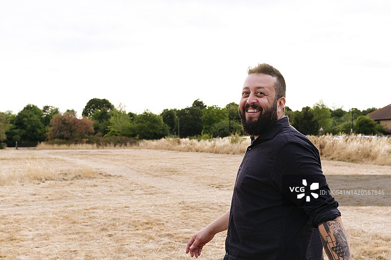 快乐的时髦男子在田野里行走图片素材