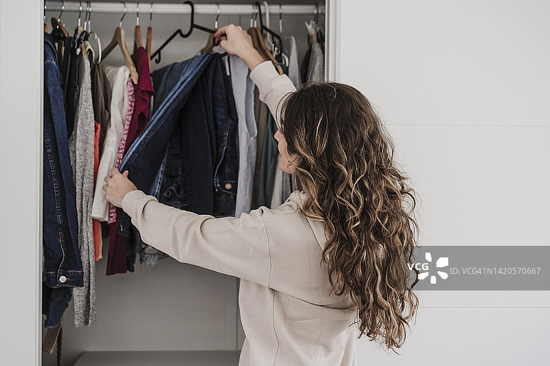 女人在家中从衣柜里挑选衣服图片素材