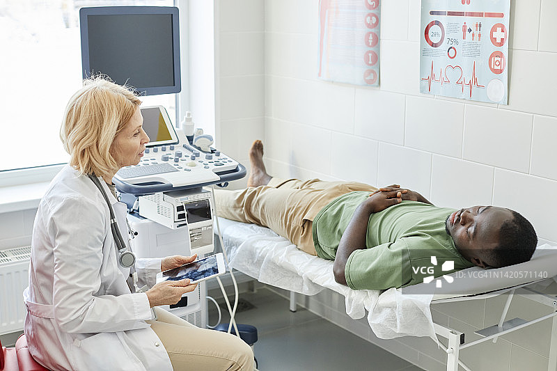 医生在诊所与卧床病人进行超声检查图片素材