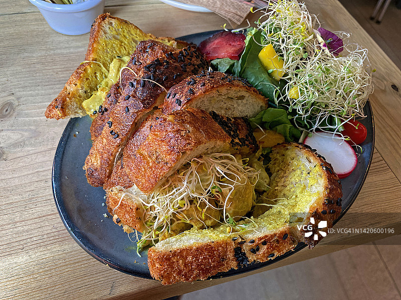 咖啡馆里盘子上放着加冕鸡肉三明治和配菜沙拉图片素材