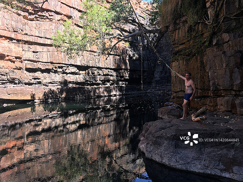 澳大利亚男子拉着连接树的绳子准备荡入水池图片素材