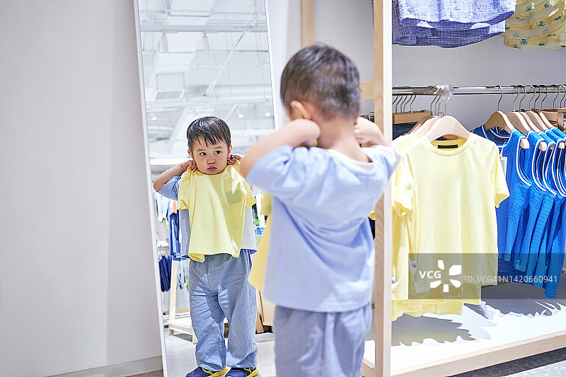 在镜子前试穿衣服的小男孩图片素材