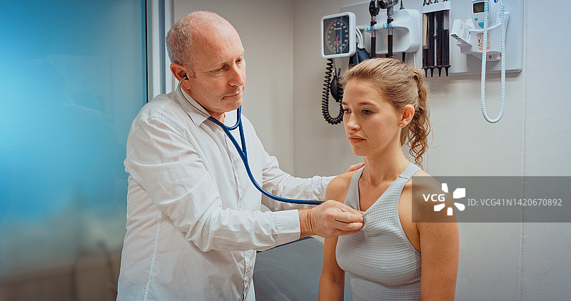 医生或心脏病专家用听诊器检查病人胸部，在医院或诊所帮助、测试或检查疼痛。心脏科医护人员在听生病年轻妇女的心跳图片素材