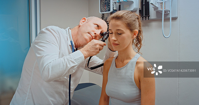 医疗健康，医生使用耳镜检查病人耳朵，并在医院预约或检查中进行咨询图片素材