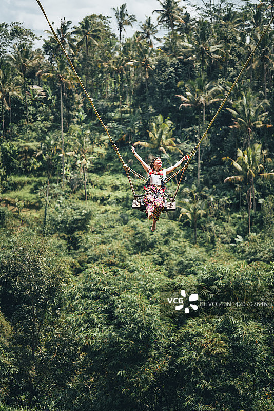 在印度尼西亚巴厘岛雨林上荡秋千的女人图片素材