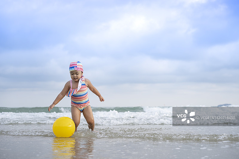 在沙滩上玩球的快乐女宝宝图片素材