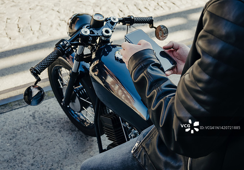 摩托车手休息时使用智能手机图片素材