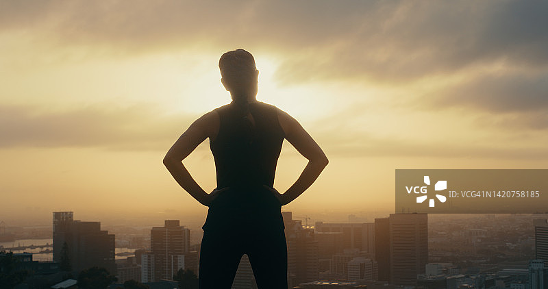 日落时分在城市背景下锻炼的女性健身剪影：马拉松训练后的动力和成功图片素材