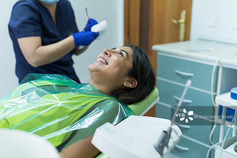 口腔检查前，病人微笑地躺在牙医面前图片素材