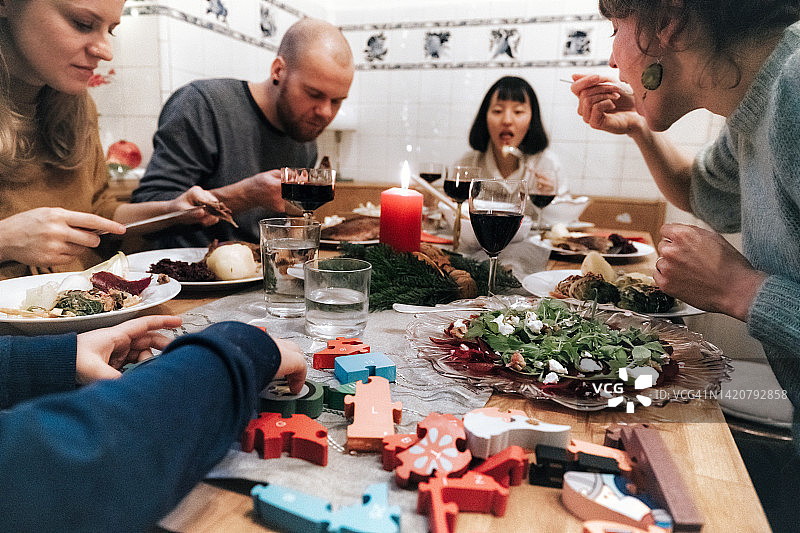 年轻家庭在圣诞餐桌上与朋友共进晚餐图片素材