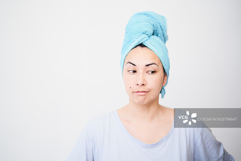 混血女人头上裹着蓝色毛巾，带着嘲讽笑容的肖像图片素材