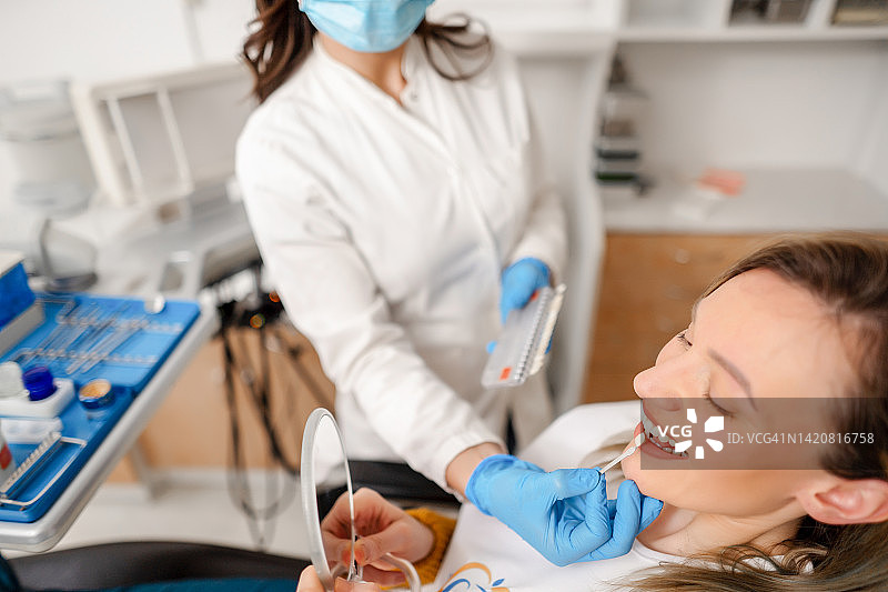 年轻的女性牙医与患者一起试戴牙贴面图片素材