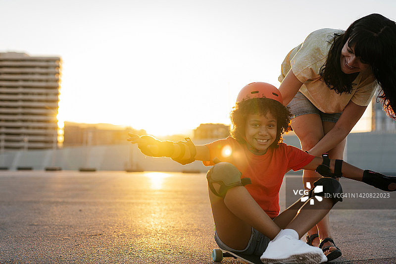 黄昏时分，母亲在郊外和女儿玩滑板图片素材