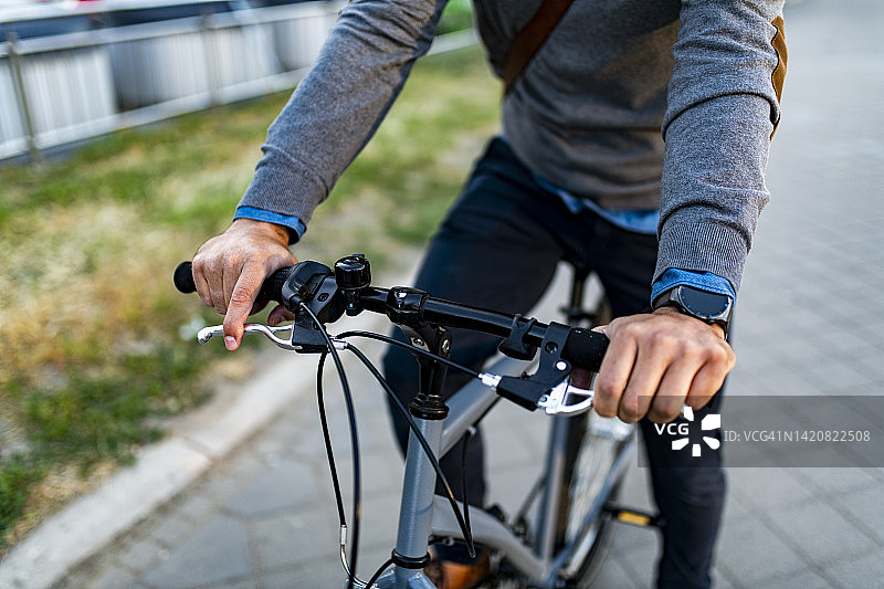 戴着手表骑自行车的时髦年轻男人的局部视图图片素材