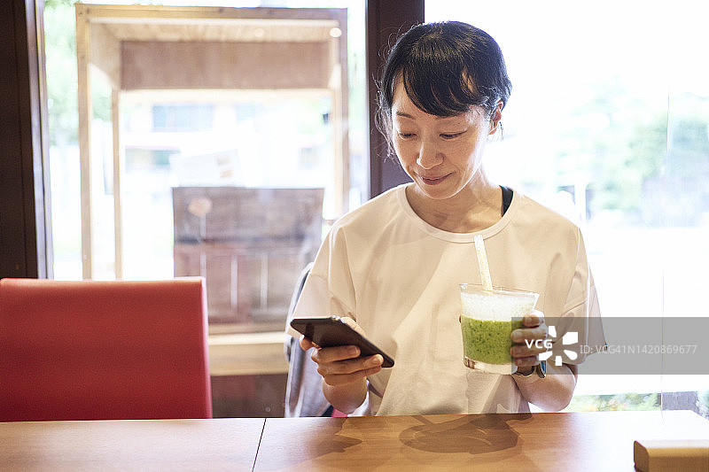 亚洲女人在素食餐厅享用小松菜香蕉冰沙图片素材