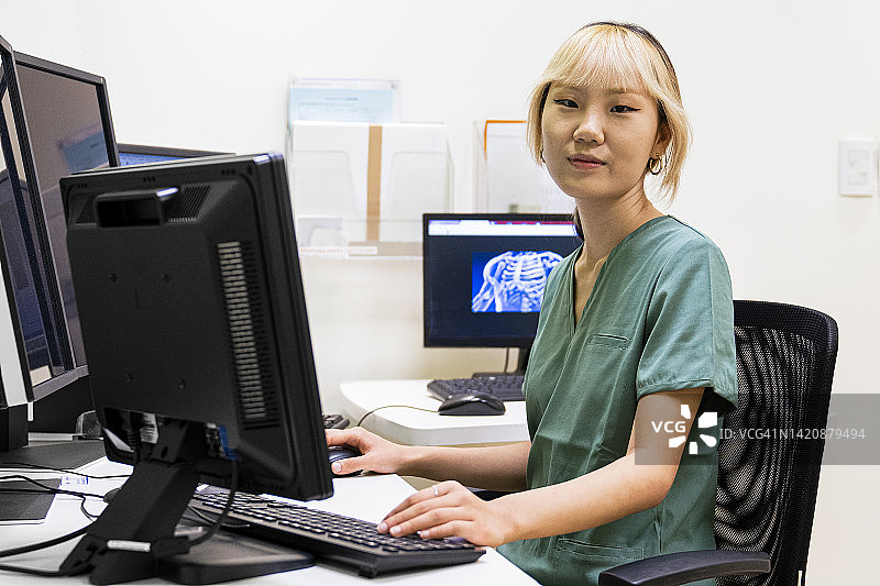 亚裔美国女诊断影像操作员检查监视器上的数据图片素材