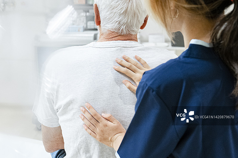 年轻女医护人员为年长的男性患者进行体检的中景图片素材