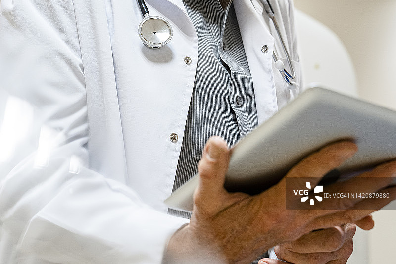 仰视角度拍摄的男医生在医疗机构内手持数字平板电脑图片素材