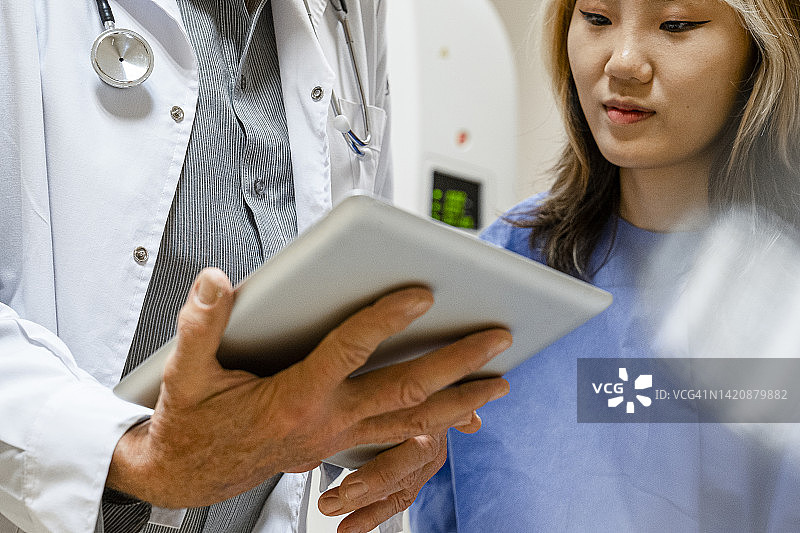 女病人看医生平板电脑屏幕的低角度视图图片素材
