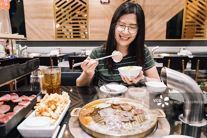 亚洲女性用筷子夹锅烧肉图片素材