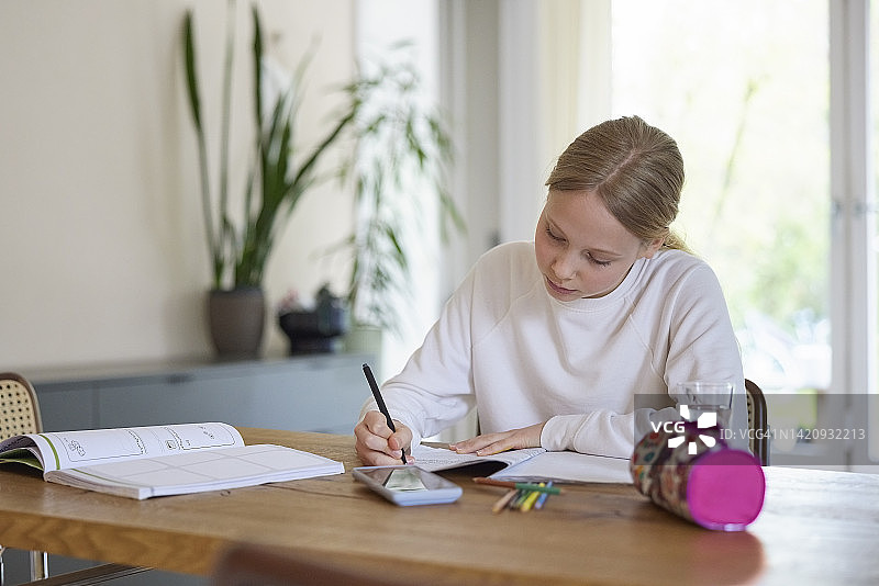 坐在客厅桌旁做作业的少女图片素材