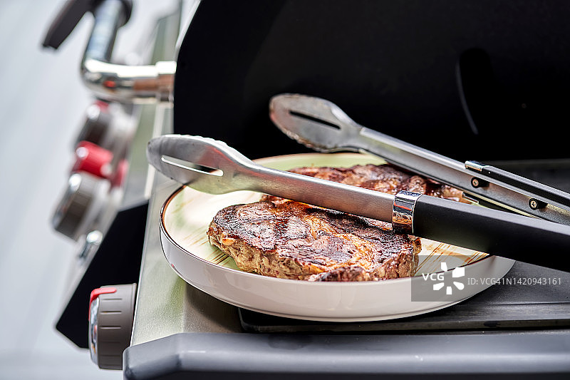 烤架上的一盘肉和烧烤钳图片素材