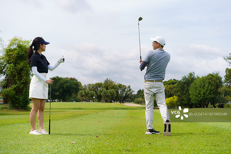 亚洲夫妇的高尔夫假期，在美丽的晴朗天气打高尔夫球。图片素材