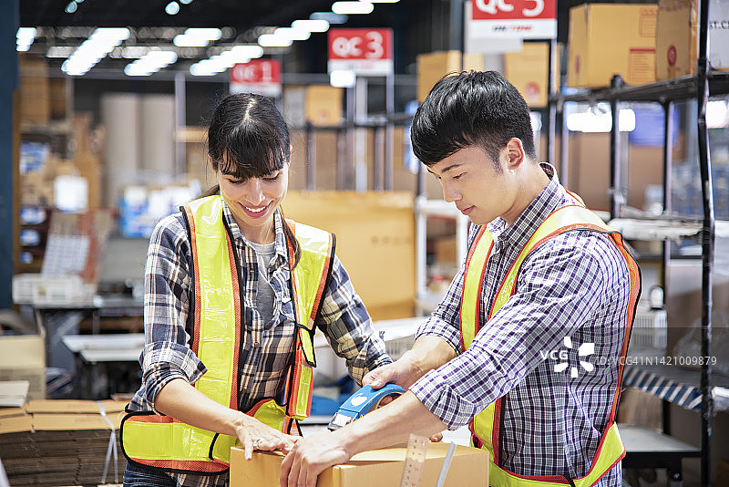 配送仓库的员工正在包装产品并检查质量控制。图片素材
