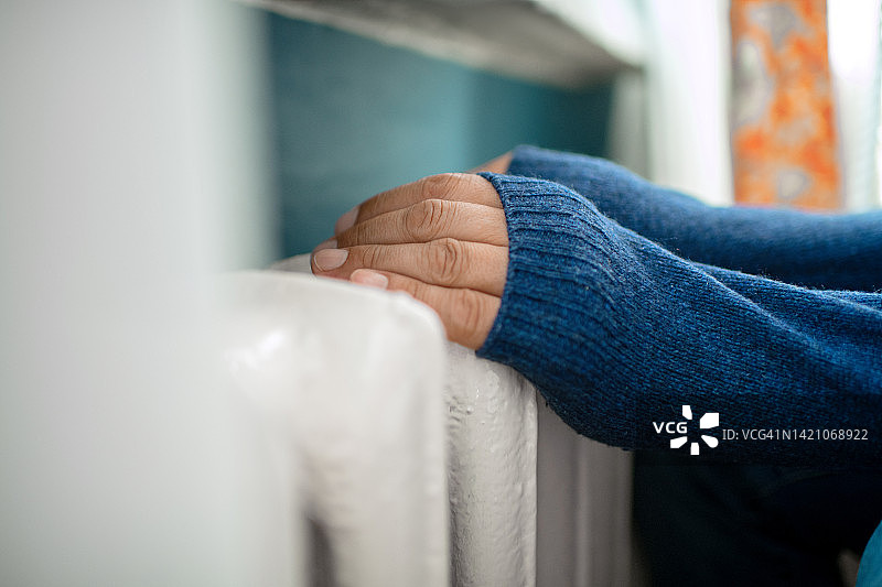 男子试图在加热器旁取暖图片素材