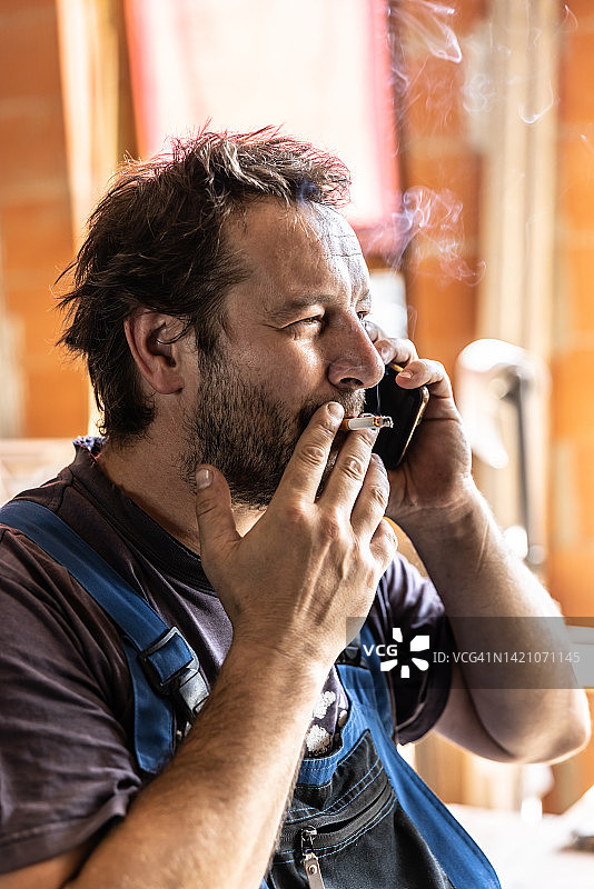 吸烟工人边抽烟边用手机图片素材