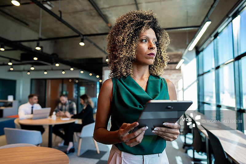 在共享办公空间手持平板电脑的商务女性图片素材