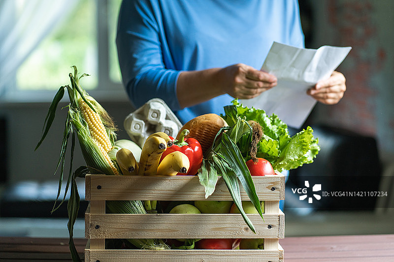 在厨房手持木制食品杂货箱的家庭主妇图片素材