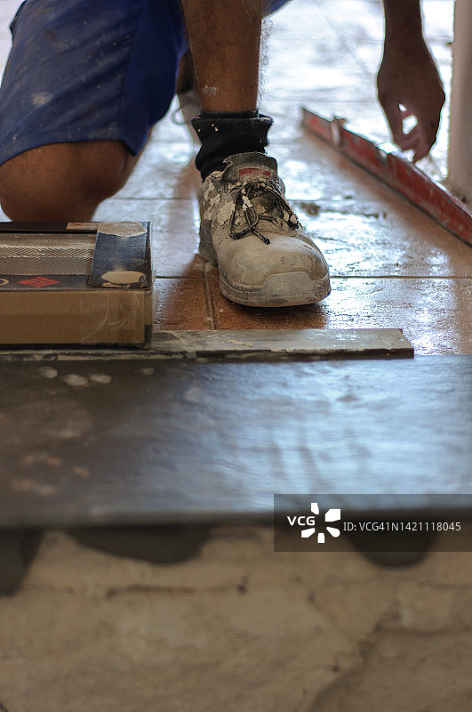 工人铺设瓷砖，可见一双脏鞋图片素材