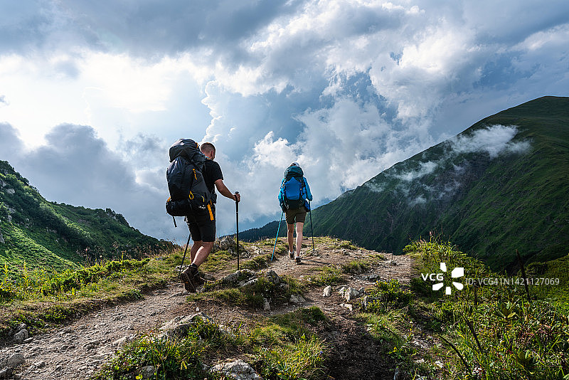 在山区高处步道柱子旁移动的徒步者图片素材