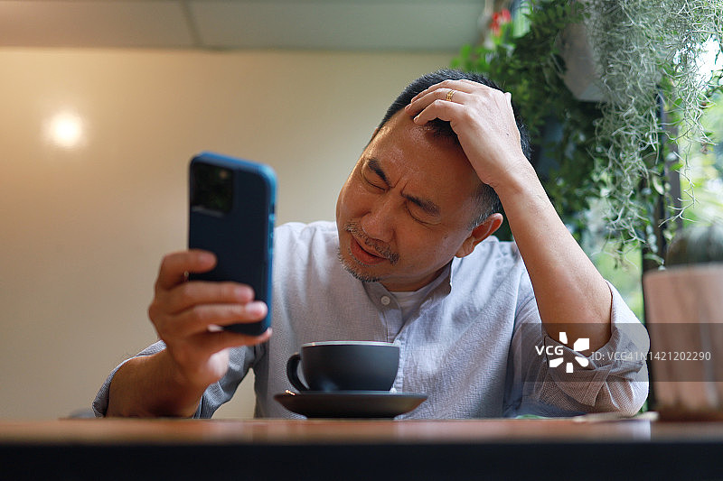 沮丧的亚洲商人用智能手机图片素材