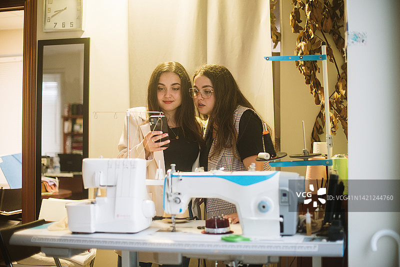 两名女子在服装定制店使用智能手机图片素材