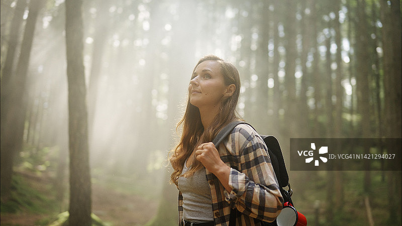 女人在雾气弥漫的森林中徒步旅行图片素材