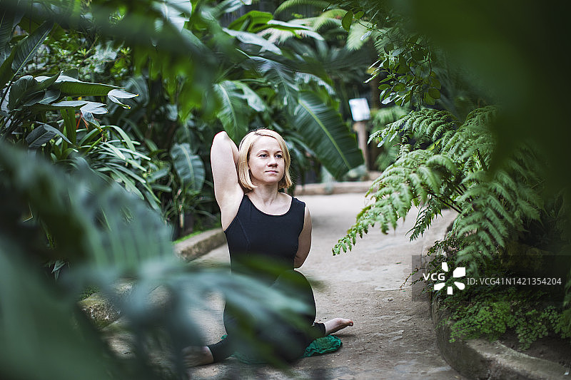 在温室中练习瑜伽的年轻女子图片素材